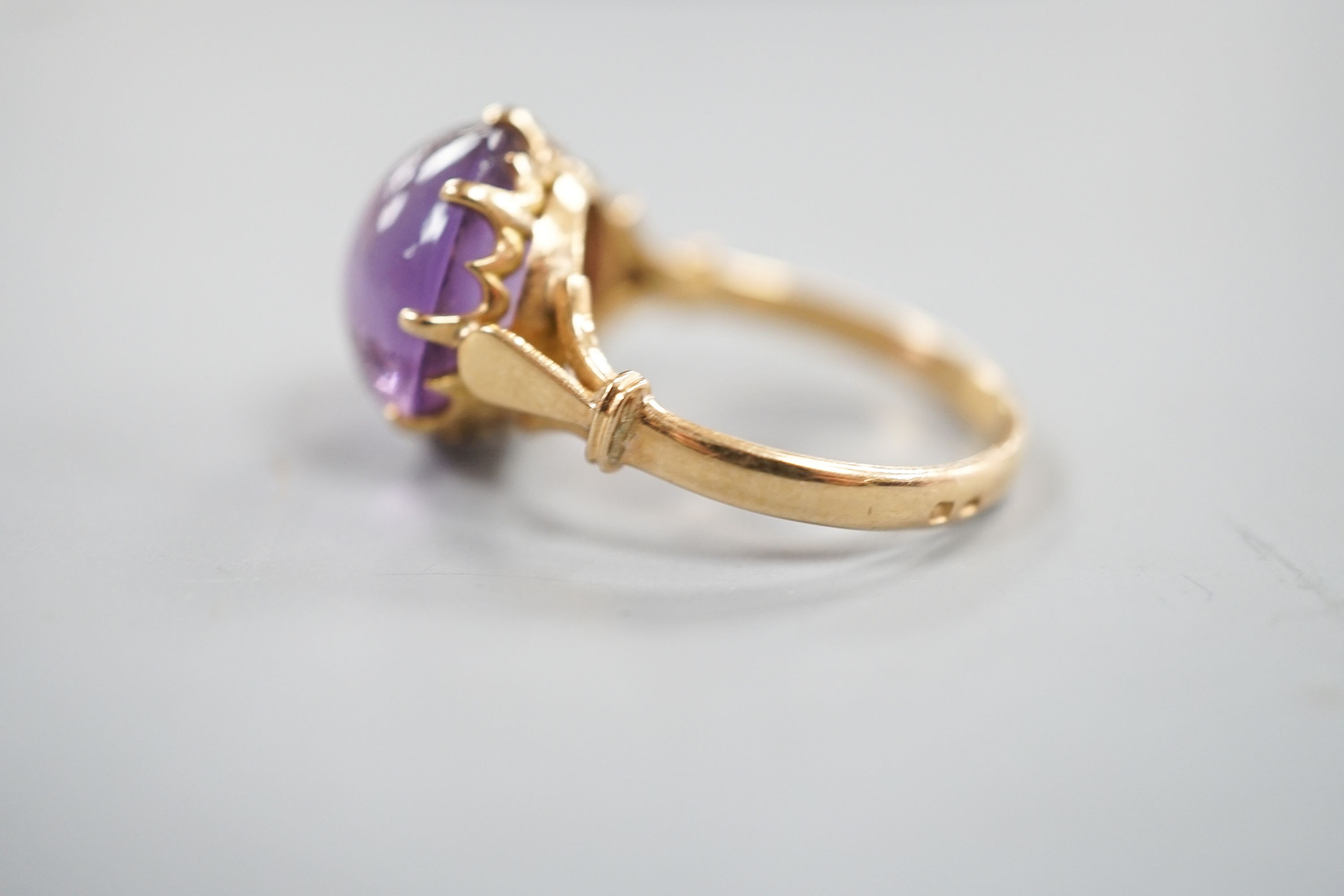 An early 20th century yellow metal and button shaped cabochon amethyst set ring, size R/S, gross weight 5.5 grams.